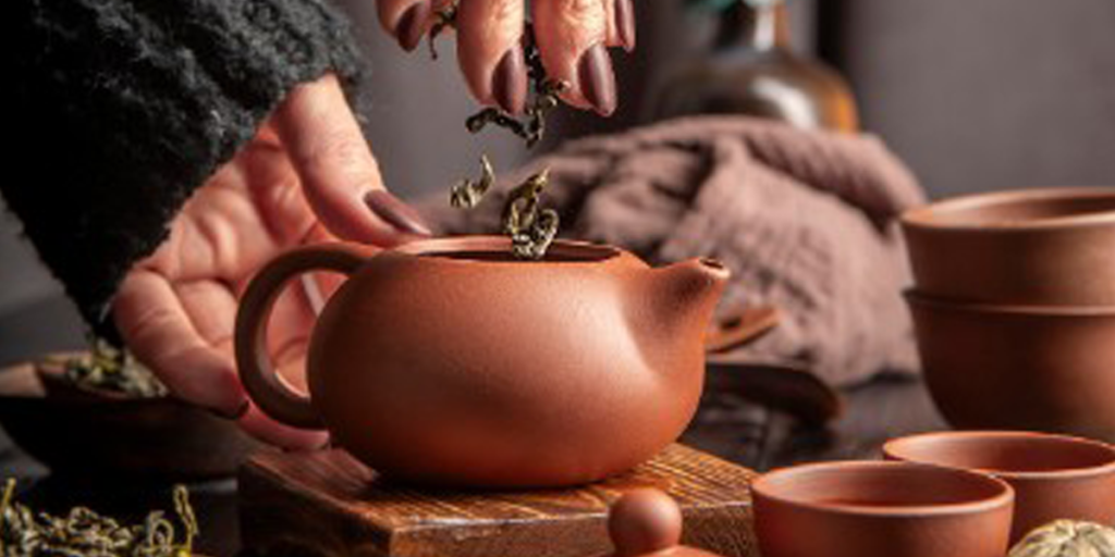 Close-up of someone pouring fresh tea into a teapot